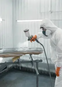 Carrossier en combinaison appliquant une peinture au pistolet